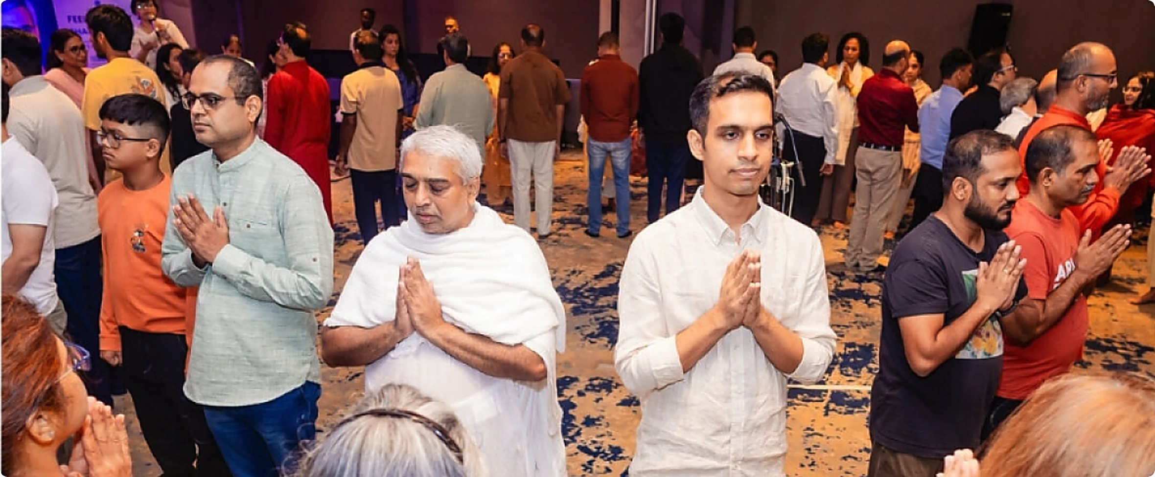 People with hands together in prayer at a Wellness Vibe gathering