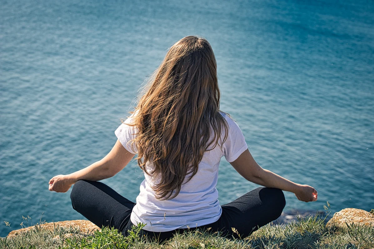 Person meditating by the water